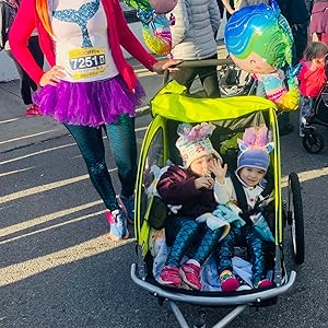 Mom with on a fun run in a tutu with two daughters in a Booyah Stroller.