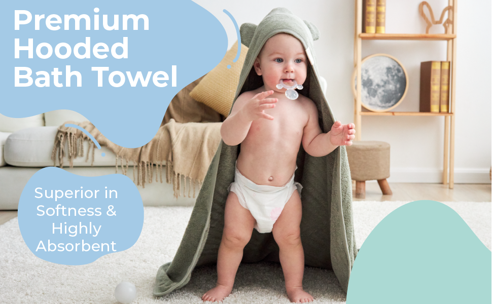 Baby stood up covered in white sage color hooded bath towel looking over sunlit window